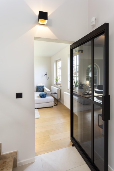 Binnendeur op maat. Zwarte steellook omkadert glazen panelen. deur waar je door kan kijken voor een modern interieur.