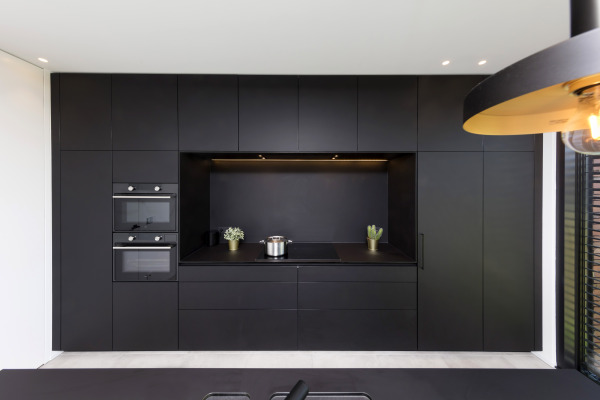 Zwarte kastenwand met nis om te koken en ledverlichting.