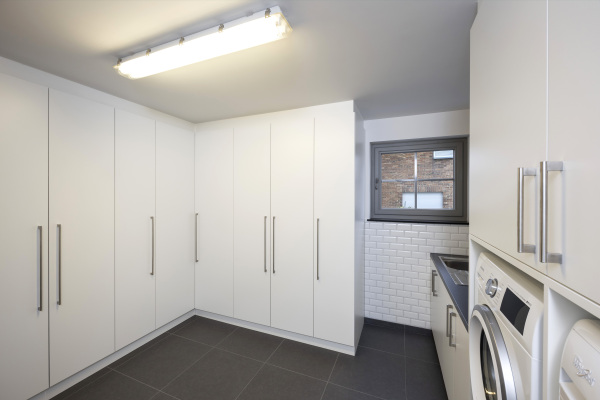 Functionele berging wasplaats met wasmachine met witte kolomkasten maatwerk.