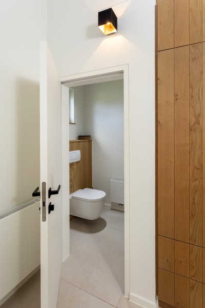 Maatwerktoiletruimte met houten wandafwerking en zwevend toilet, combineert functionaliteit met een warme uitstraling.